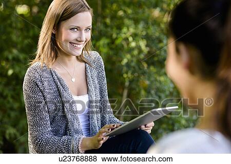 Two young women with digital tablet in park View Large Photo Image Stock Photo - Two young women with digital tablet in park. Fotosearch