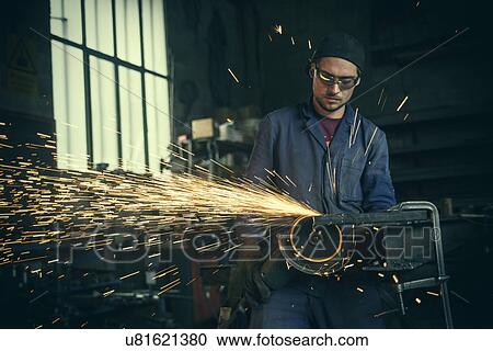 Stock Image - Welder cutting iron in workshop. Fotosearch