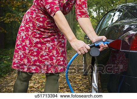 Woman charging electric car in forest View Large Photo Image Picture - Woman charging electric car in forest. Fotosearch