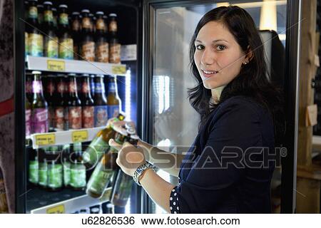 Woman filling fridge with drinks bottles in shop View Large Photo Image Stock Photograph - Woman filling fridge with drinks bottles in shop. Fotosearch