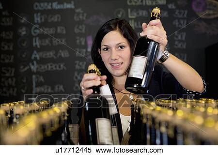 Stock Photography - Woman holding bottles of wine in shop. Fotosearch
