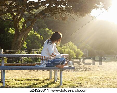 Stock Image - "Woman resting on park bench, Roadknight, Victoria, Australia". Fotosearch