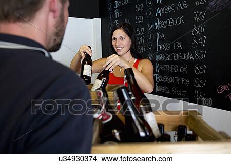 Woman serving man in off license View Large Photo Image Picture - Woman serving man in off license. Fotosearch
