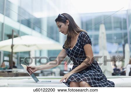 Woman using laptop by outdoor cafe View Large Photo Image Stock Image - Woman using laptop by outdoor cafe. Fotosearch