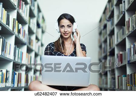 Woman wearing headphones studying in the library View Large Photo Image Stock Photo - Woman wearing headphones studying in the library. Fotosearch