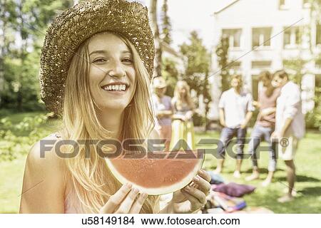 Picture - Woman wearing straw hat eating watermelon. Fotosearch