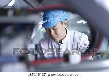 Stock Photo - Worker using machinery in factory that specialises in creating functional circuits on flexible surfaces. Fotosearch