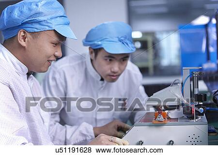 Stock Photo - Workers using machinery in factory that specialises in creating functional circuits on flexible surfaces. Fotosearch