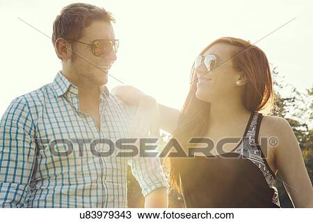 Young couple gazing at each other in park View Large Photo Image Stock Image - Young couple gazing at each other in park. Fotosearch