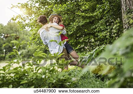 Stock Image - Young couple hugging and laughing in garden. Fotosearch