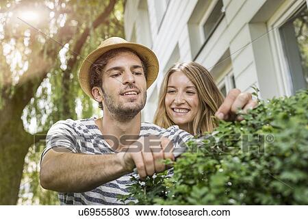 Young couple pruning bush outside house View Large Photo Image Stock Image - Young couple pruning bush outside house. Fotosearch