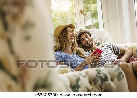Young couple reading message on smartphone in living room View Large Photo Image Stock Image - Young couple reading message on smartphone in living room. Fotosearch