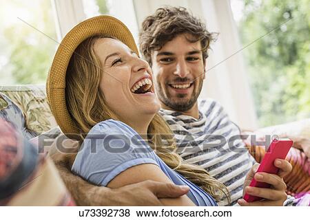 Young couple texting on smartphone in living room View Large Photo Image Stock Photo - Young couple texting on smartphone in living room. Fotosearch