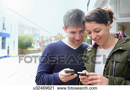 Young couple using smartphones View Large Photo Image Stock Image - Young couple using smartphones. Fotosearch