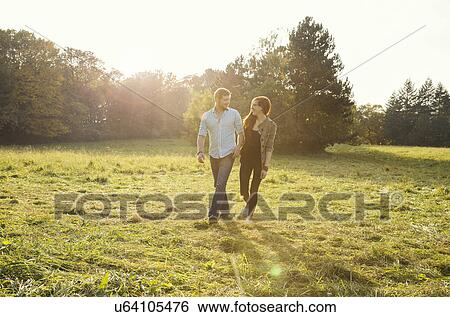 Young couple walking hand in hand in park View Large Photo Image Stock Photograph - Young couple walking hand in hand in park. Fotosearch