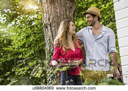 Stock Photo - Young couple with flower basket in garden. Fotosearch