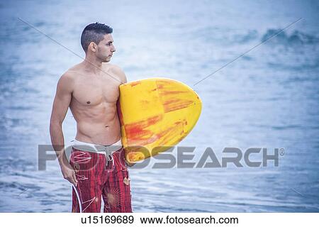 "Young male surfer carrying surfboard on beach, Cagliari, Sardinia, Italy" View Large Photo Image Stock Photo - "Young male surfer carrying surfboard on beach, Cagliari, Sardinia, Italy". Fotosearch