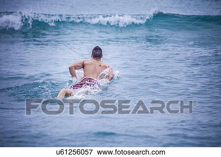 "Young male surfer lying on surfboard in sea, Cagliari, Sardinia, Italy" View Large Photo Image Stock Photo - "Young male surfer lying on surfboard in sea, Cagliari, Sardinia, Italy". Fotosearch