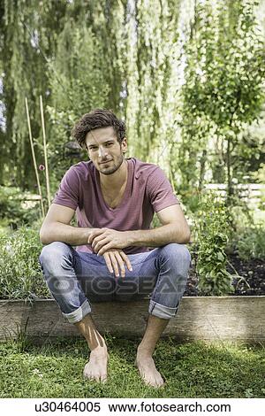 Young man sitting in garden View Large Photo Image Stock Photography - Young man sitting in garden. Fotosearch