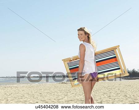 "Young woman carrying deck chair on beach, Altona, Melbourne, Victoria, Australia" View Large Photo Image Stock Photo - "Young woman carrying deck chair on beach, Altona, Melbourne, Victoria, Australia". Fotosearch
