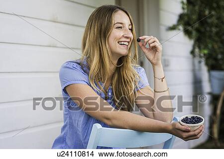 Young woman eating blueberries in front porch View Large Photo Image Picture - Young woman eating blueberries in front porch. Fotosearch
