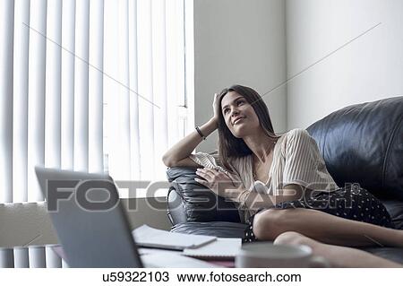 Young woman reclining on sofa View Large Photo Image Stock Image - Young woman reclining on sofa. Fotosearch