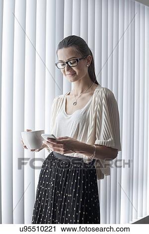 Young woman using smartphone with coffee View Large Photo Image Stock Image - Young woman using smartphone with coffee. Fotosearch