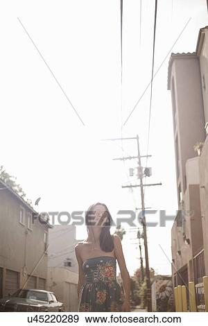 "Young woman walking down street, low angle view" View Large Photo Image Stock Photo - "Young woman walking down street, low angle view". Fotosearch
