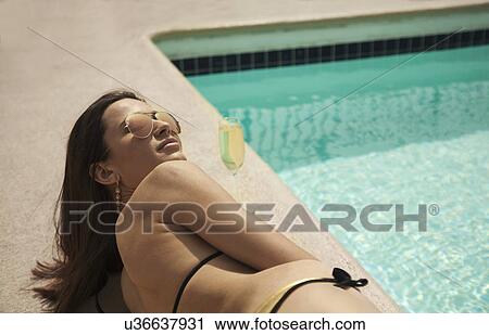 Young woman wearing bikini lying poolside View Large Photo Image Stock Image - Young woman wearing bikini lying poolside. Fotosearch