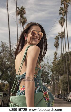 Stock Photo - "Young woman wearing sundress, looking over shoulder". Fotosearch