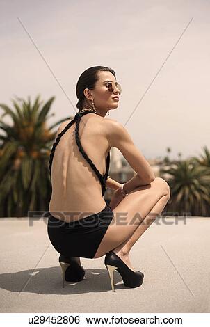 Stock Photograph - "Young woman wearing swimsuit crouching, portrait". Fotosearch