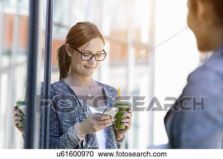 Young woman with takeaway coffee reading smartphone messages View Large Photo Image Stock Image - Young woman with takeaway coffee reading smartphone messages. Fotosearch