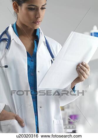 Doctor reading a patient's notes View Large Photo Image Stock Photograph - Doctor reading a patient's notes. Fotosearch