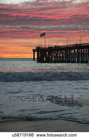Stock Photograph - "American flag flies over Ventura Pier at sunset, Ventura, California, USA". Fotosearch