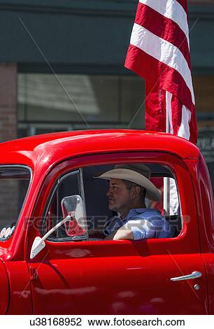Stock Image - "Antique Red Truck and cowboy drive in July 4, Independence Day Parade, Telluride, Colorado, USA". Fotosearch