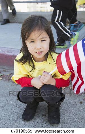 Stock Photography - "Chinese American girl holds flag, 115th Golden Dragon Parade, Chinese New Year, 2014, Year of the Horse, Los Angeles, California, USA". Fotosearch