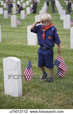 Stock Image - "Cubscout salutes after placing one of 85, 000 US Flags at 2014 Memorial Day Event, Los Angeles National Cemetery, California, USA". Fotosearch