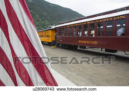 Stock Image - "US Flag and Durango and Silverton Narrow Gauge Railroad Steam Engine Train, Silverton, Colorado, USA". Fotosearch