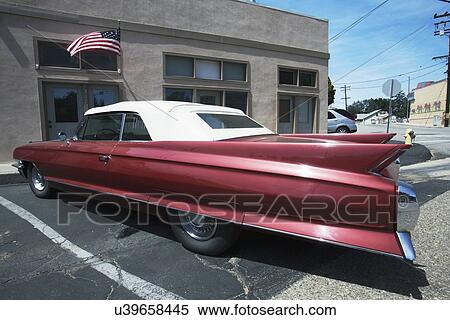 Stock Photography - "Vintage Cadilac and US Flag parked in front of Saddle Shop, Oak View, California, USA". Fotosearch