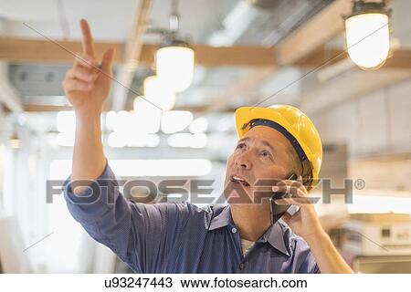 Stock Image - Architect in hardhat talking on mobile phone. Fotosearch