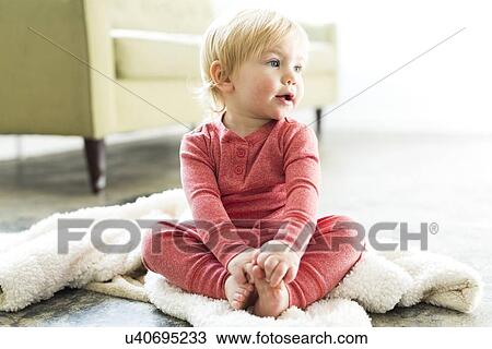 Stock Image - Baby boy (2-3) sitting on blanket in living room. Fotosearch