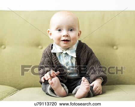 Stock Image - Baby boy (6-11 months) sitting on sofa. Fotosearch