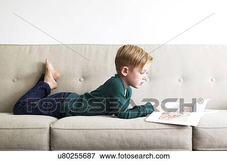 Boy (2-3) reading book on sofa View Large Photo Image Stock Photo - Boy (2-3) reading book on sofa. Fotosearch