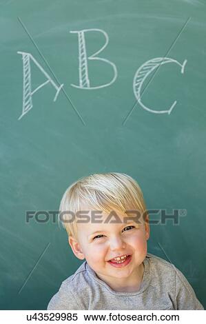 Boy (2-3) smiling in front of blackboard with letters ABC written on it View Large Photo Image Stock Photography - Boy (2-3) smiling in front of blackboard with letters ABC written on it. Fotosearch