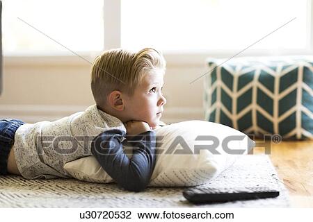 Stock Image - Boy (4-5) watching tv in living room. Fotosearch