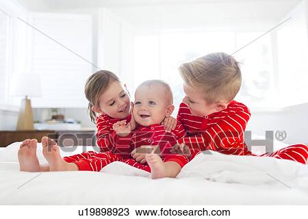 Boy (6-7) and girl (4-5) embracing brother (2-3) on bed View Large Photo Image Stock Image - Boy (6-7) and girl (4-5) embracing brother (2-3) on bed. Fotosearch