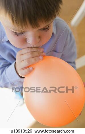 Boy (6-7) inflating balloon View Large Photo Image Stock Photograph - Boy (6-7) inflating balloon. Fotosearch