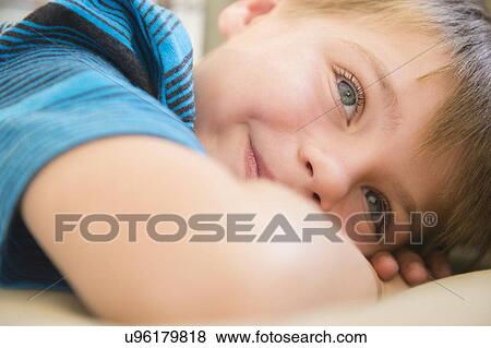 Stock Photo - Boy (6-7) relaxing on sofa. Fotosearch