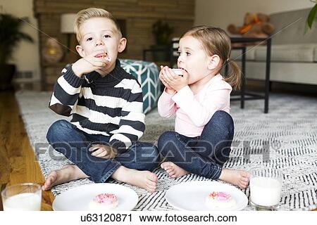 Brother (6-7) and sister (4-5) eating cookies in living room View Large Photo Image Stock Image - Brother (6-7) and sister (4-5) eating cookies in living room. Fotosearch