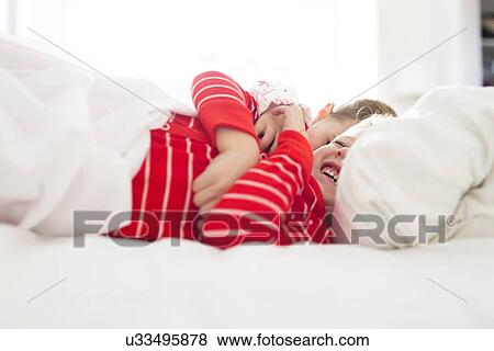 Brother (6-7) and sister (4-5) laughing in bed View Large Photo Image Stock Photo - Brother (6-7) and sister (4-5) laughing in bed. Fotosearch